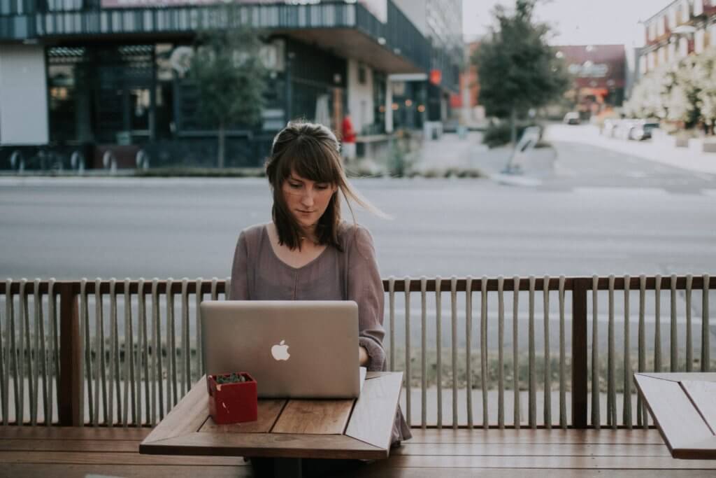 Brunette woman sitting at outdoor cafe, working at her laptop