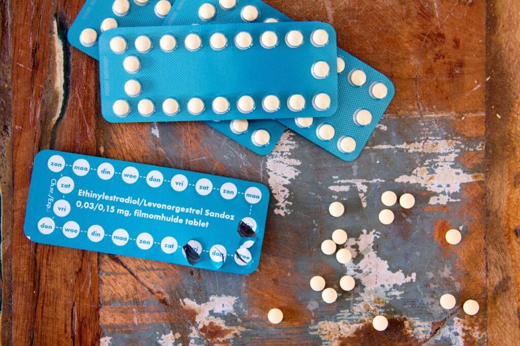 Birth control pills in blue packaging on brown table