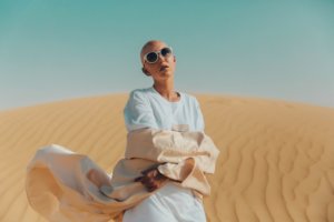 Bald woman with henna wearing flowing clothing in dessert